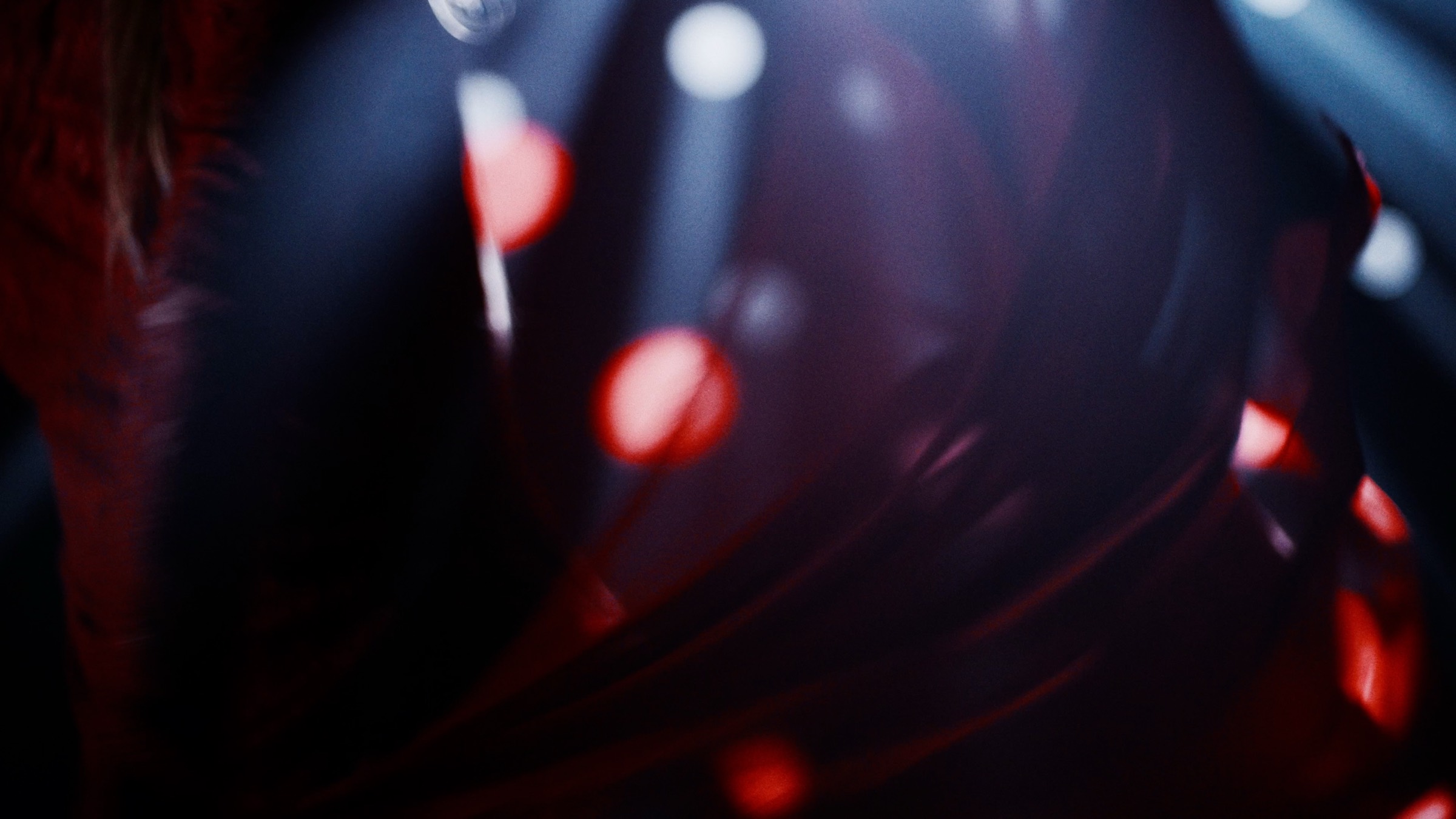 Reflets rouges et blancs flous dans une surface sombre et courbe.